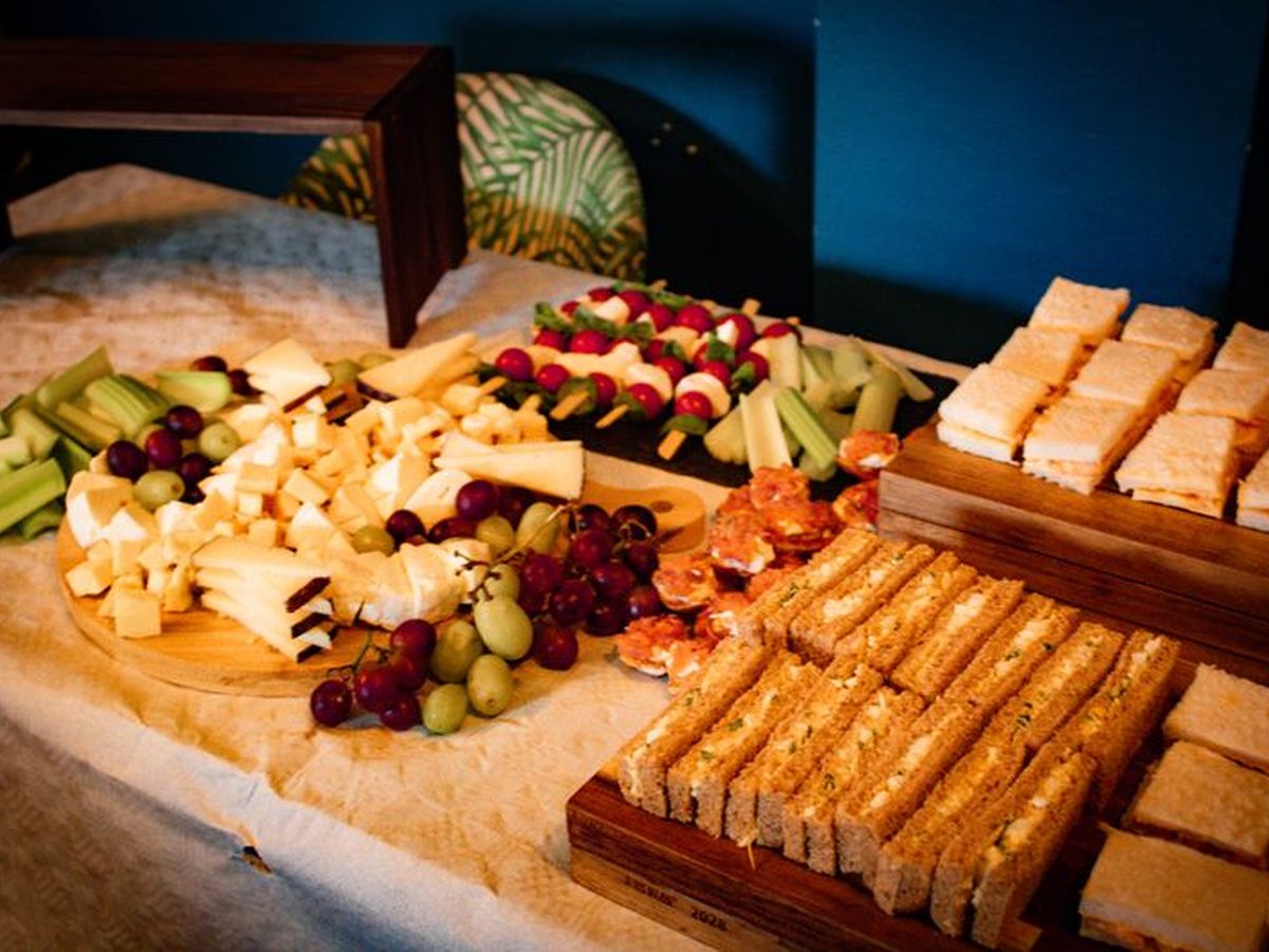A buffet-style spread with sandwiches, cheese, fruit and savoury bites for an event